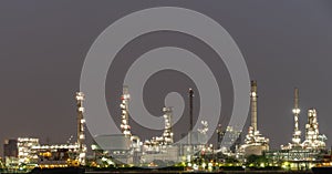 Night photo crude oil refinery plant and many chimney with petrochemical tanker or cargo ship at coast of the river with colorful