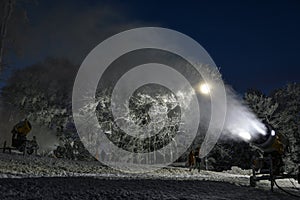 Night photo of snow cannon or snowmaking machine in action in ski resort.