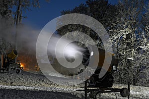 Night photo of snow cannon or snowmaking machine in action in ski resort.