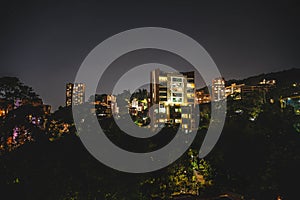 night photograph of el poblado medellin with apartment building in foreground with stars and mountains in background photo