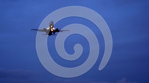 Night, plane flies in the sky. Dark blue sky, clouds are visible on horizon