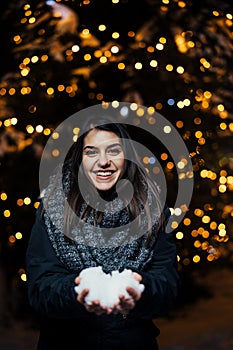 Night portrait of a beautiful brunette woman smiling enjoying winter in park.Winter joy.Winter holidays.Positive emotions.
