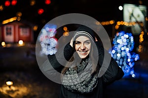 Night portrait of a beautiful brunette woman smiling enjoying winter in park.Winter joy.Winter holidays.Positive emotions.