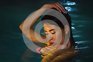Night portrait of brunette woman swimming in pool with hot mineral water in balneotherapy spa photo