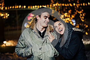 Night portrait of a happy couple smiling enjoying winter and snow aoutdoors.Winter joy.Positive emotions.Happiness