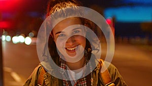 Night portrait of happy female tourist traveling and enjoying the city nightlife. Cute laughing young woman standing