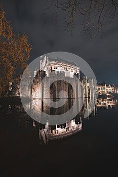 Night portrait of the medieval Gravesteen Castle in the centre of Ghent, Belgium. The reflection of the walls is in the water