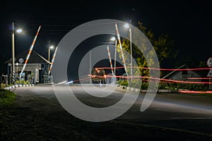 Night railway crossing with passing cars