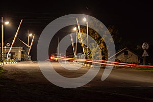 Night railway crossing with passing cars