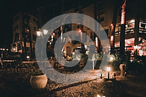 Night scene of an elegant outdoor bar illuminated by small lamps among the trees and plants