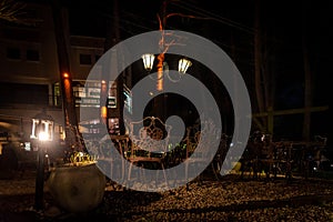 Night scene of an elegant outdoor bar illuminated by small lamps among the trees and plants