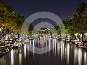 Night scene with a canal and illuminated embankment in Amsterdam, The Netherlands