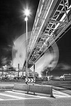Night scene with illuminated petrochemical production plant and pipeline bridge