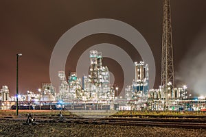Night scene with illuminated petrochemical production plant and train tracks, Antwerp, Belgium