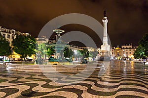 Night scene of Rossio Square, Lisbon, Portugal with one of its decorative fountains and the Column of Pedro IV