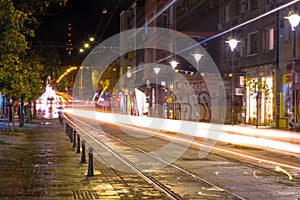 Night scene of tram in traffic at crossing with lighttrail motion blur