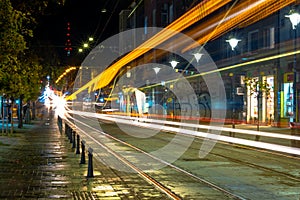 Night scene of tram in traffic at crossing with lighttrail motion blur