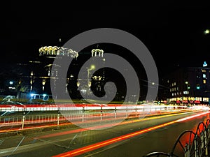 Night scene of tram in traffic at crossing with lighttrail motion blur