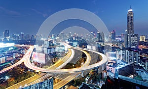 Night scenery of Bangkok with skyscrapers in background and busy traffic trails on elevated expressways & circular interchanges photo