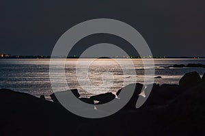 Night on seashore, moon reflections in sea