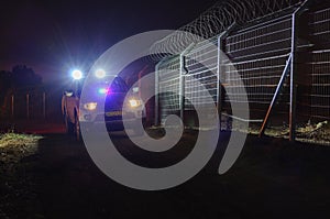 Night, security patrol car moving along the fence