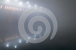 Night shot of a bridge in thick fog.