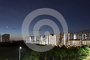 Night shot of condominium with moon, blue sky and night lights. landscape slow shutter shot of residential condos with car trails