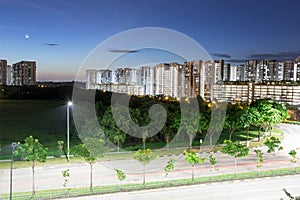 Night shot of condominium with moon, blue sky and night lights. landscape slow shutter shot of residential condos with car trails