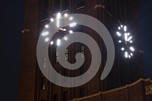 Night shot of a lit clock at the tower from a historic industrial building in Berlin