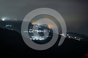 Night shot showing darjeeling village nestled in the middle of himalaya mountains with orange and blue lights