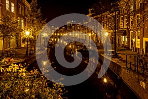 A night shot from the Sint Jansbrug on the Oude Rijn with numerous boats and illuminated old canal-side houses, Leiden, the Nether