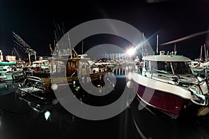 Night shot of wooden and motorboats moored at sea port