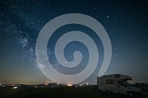 Night sky landscape in Orcia Valley, Tuscany, Italy. The Milky Way galaxy and stars over a camper van parked in the hill range