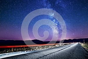 Night sky with milky way and stars. Night road illuminated by car