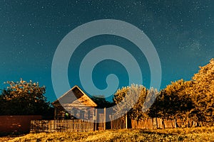 Night sky over house in old village. Night starry sky above house with bright stars and meteoric track trail. Glowing