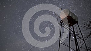 Night sky with rotating stars and constellations and tower filmed from below in timelapse