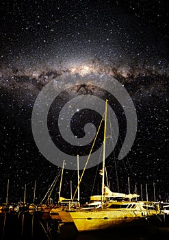 Night sky showing stars and milky way with boats in the foreground