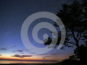 Night sky stars observing Perseus constellation over sea