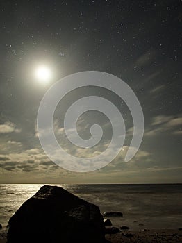 Night sky stars Pleiades and Moon set observing over sea coast