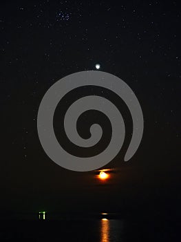 Night sky stars Pleiades Venus and Moon set observing over sea coast