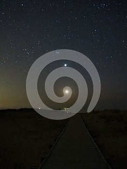 Night sky stars Pleiades Venus and Moon set observing over sea coast