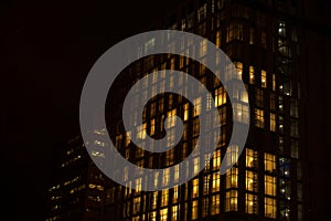 Night skyscraper close up, glowing window. Night work.Horizontal frame