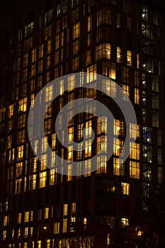 Night skyscraper close up, glowing window. Night work.Vertical shot