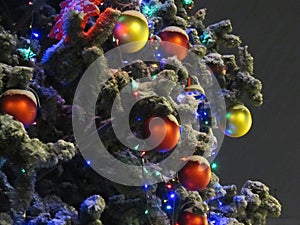 Night snapshot. Elegant Christmas tree decorated with Christmas toys, balls and garland