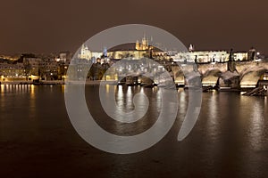 Night snowy colorful Prague Lesser Town with gothic Castle, St. Nicholas` Cathedral and Charles Bridge, Czech republic