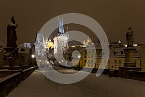 Night snowy colorful Prague Lesser Town with gothic Castle, St. Nicholas` Cathedral from Charles Bridge, Czech republic