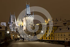 Night snowy colorful Prague Lesser Town with gothic Castle, St. Nicholas` Cathedral from Charles Bridge, Czech republic