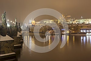 Night snowy Prague gothic Castle with Charles Bridge and St. Nicholas' Cathedral , Czech republic