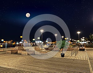 Night starry sky full moon t at pier lantern blurred light on horizon port of Tallinn Baltic bike near bench on promenade E