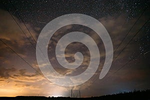 Night Starry Sky With Glowing Stars And Meteoric Track Trail Above Countryside Landscape. Light Cloudiness Overcast